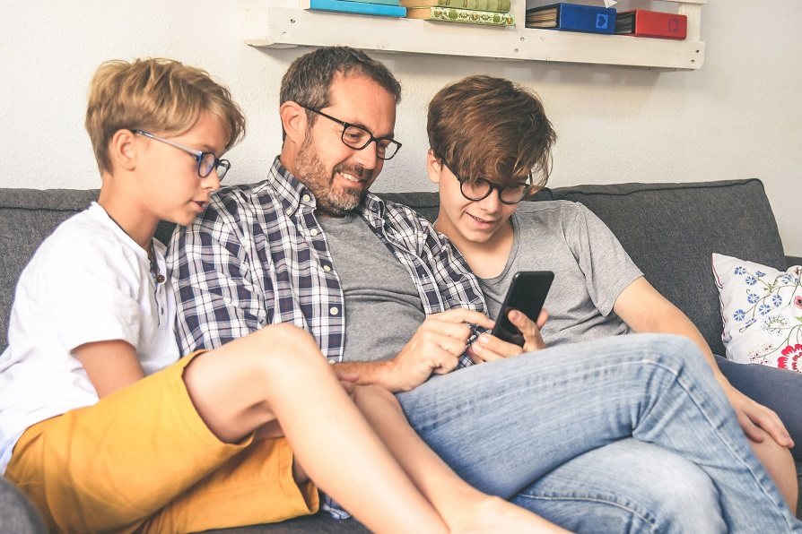 un père et ses enfants devant un smartphone